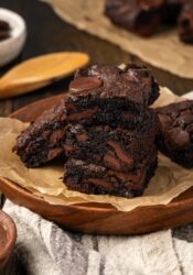 A stack of fudgy cake mix brownies on a plate lined with parchment paper.