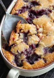 A serving spoon scooping out blackberry cobbler