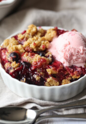 Mixed Berry Crisp in a white dish topped with a scoop of strawberry ice cream.