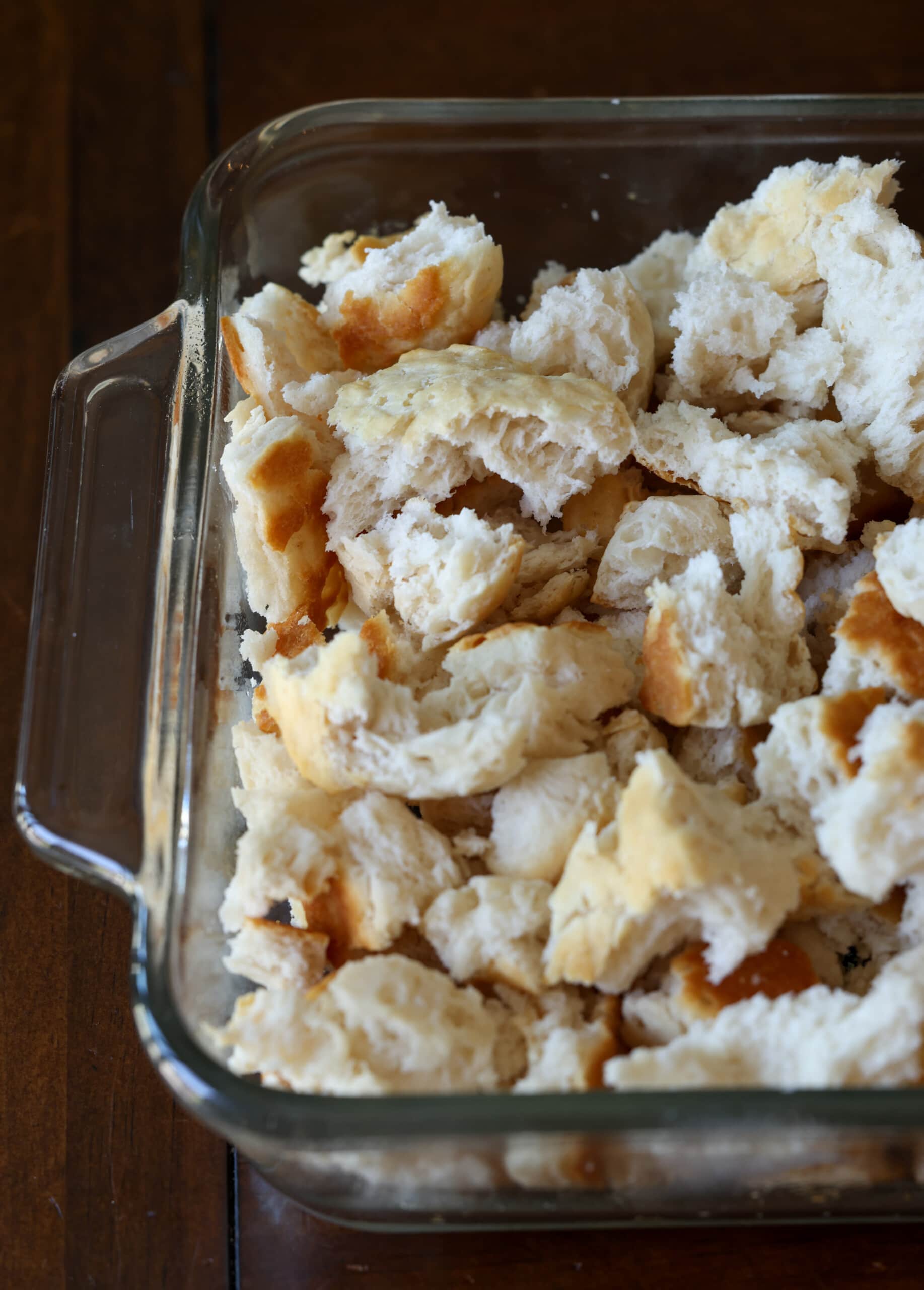 torn and crumbled day old biscuits in a 8x8 glass baking pan