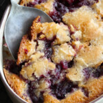 A serving spoon scooping out blackberry cobbler