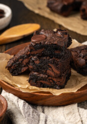 A stack of fudgy cake mix brownies on a plate lined with parchment paper.