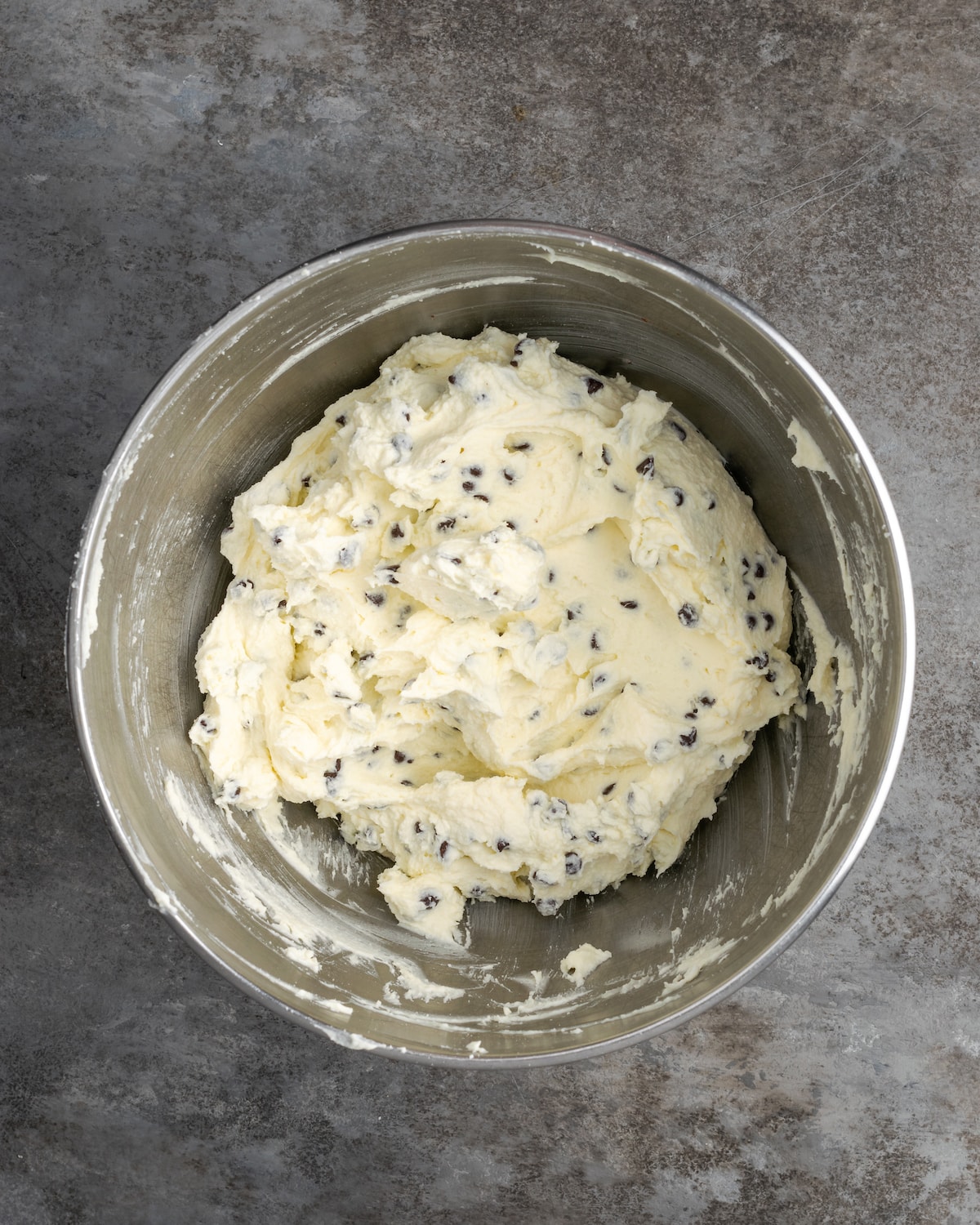 Chocolate chips added to the mascarpone filling ingredients in a metal mixing bowl.