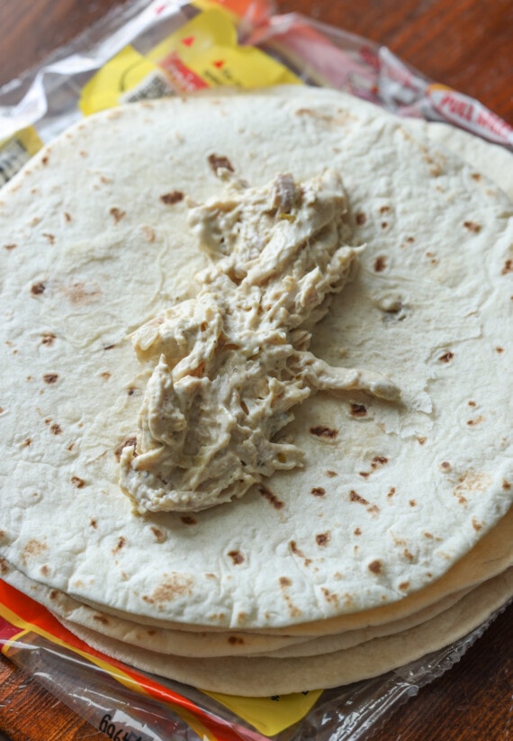 creamy chicken mixture on top of a flour tortilla before being rolled up