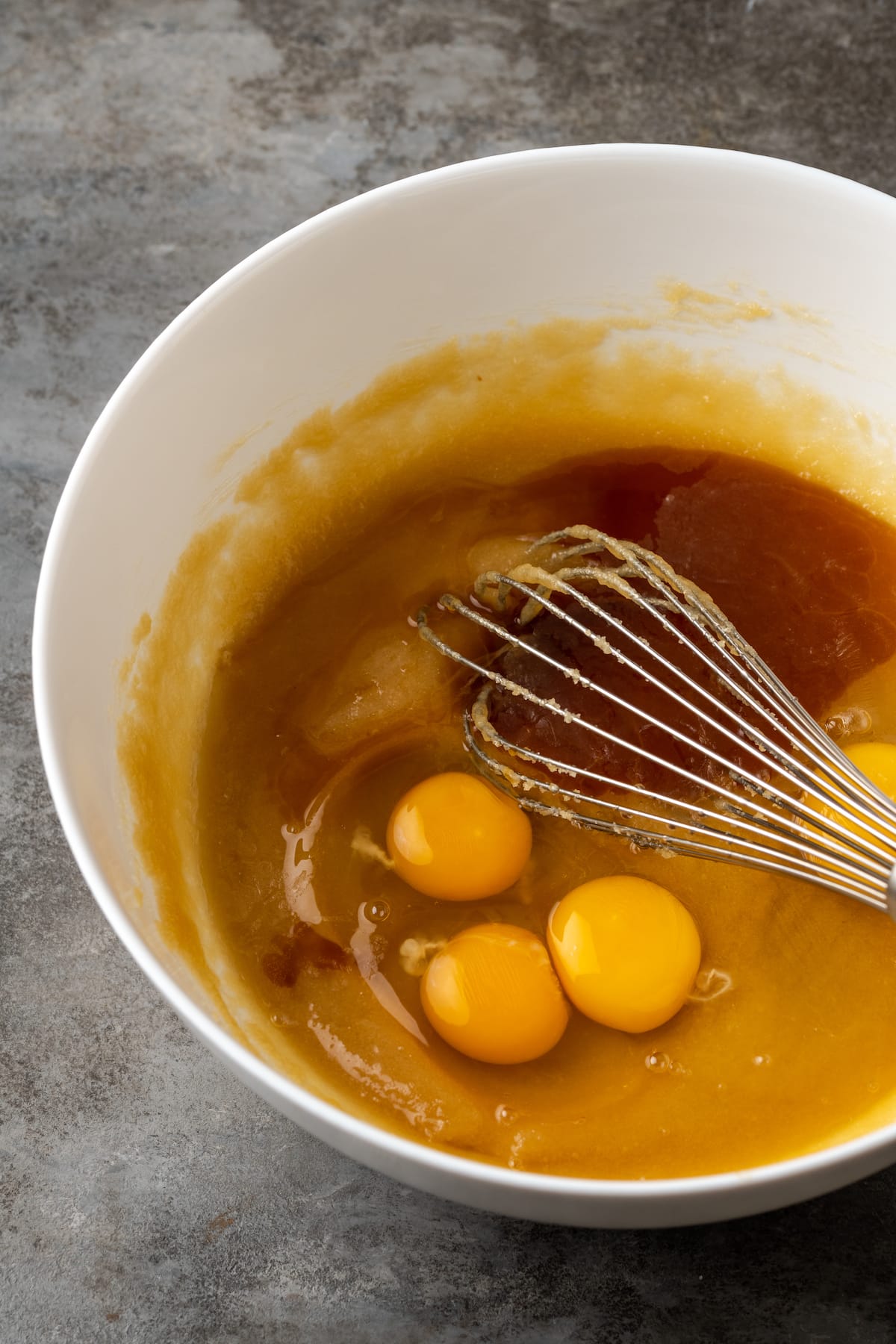 Eggs and vanilla whisked into creamed sugar and butter in a mixing bowl.