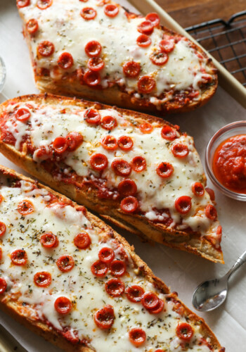 Three French bread pizzas on a platter.