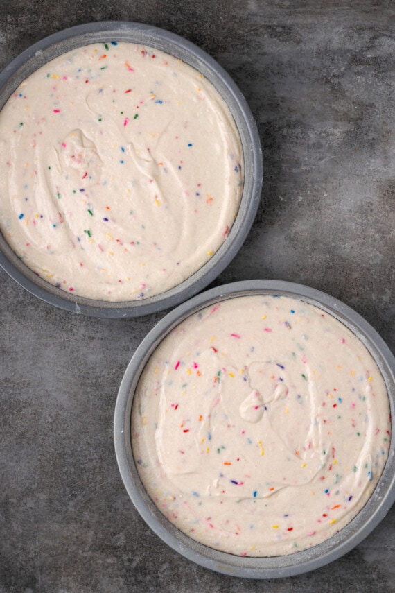 Overhead view of two round cake pans filled with confetti cake batter.