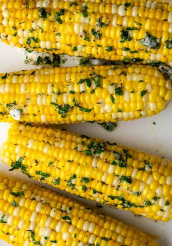 Top view of corn on the cob coated with butter and herbs.
