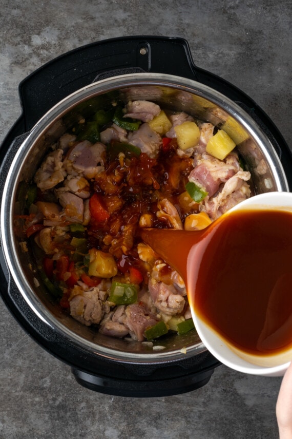 Sauce is poured over Hawaiian chicken ingredients inside the Instant Pot.