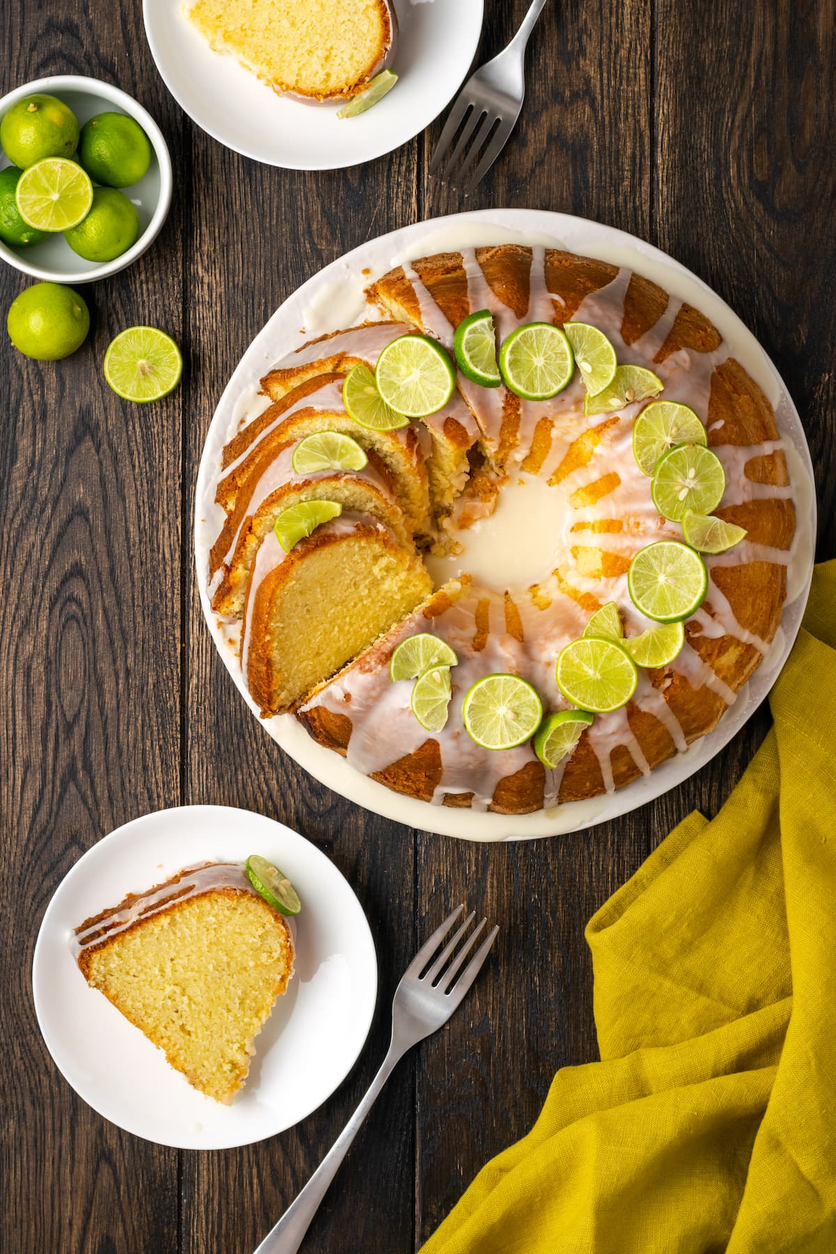 Overhead view of a whole Key lime pound cake cut into slices, next to a slice served on a white plate.