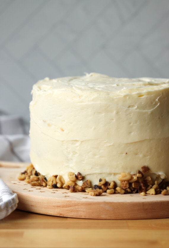 a whole cake covered with cream cheese frosting and garnished with walnuts at the bottom