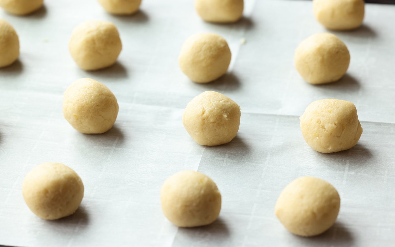 cookie dough balls on a parchment lined cookie sheet