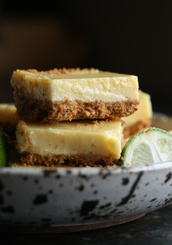 Pretzel Crusted Key Lime Bars stacked in a bowl next to a key lime wedge.