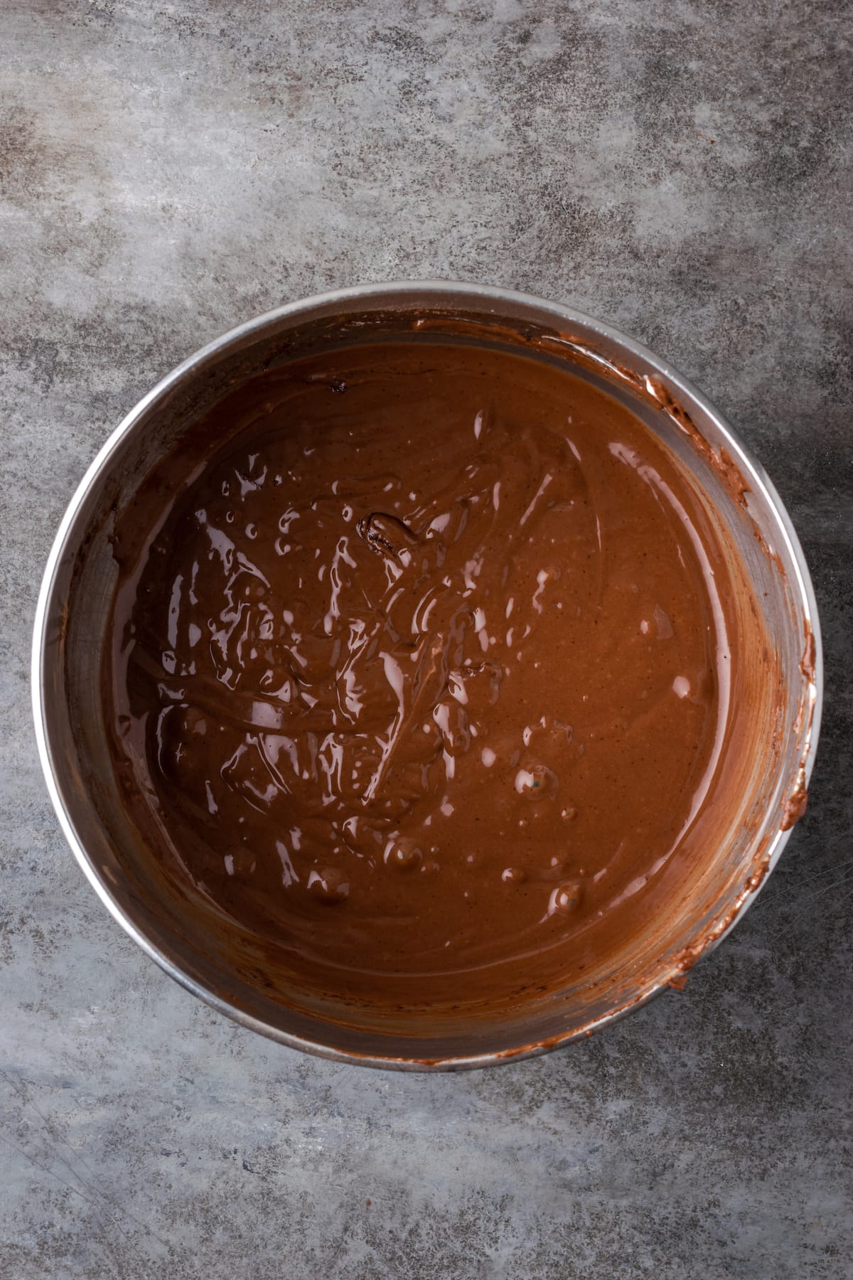 Chocolate cake batter in a metal mixing bowl.