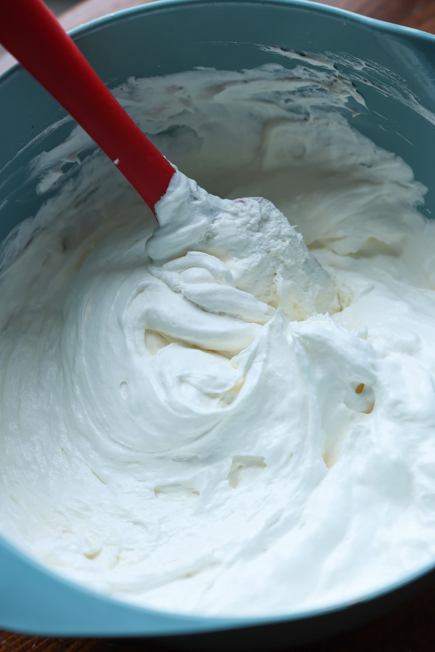 cream cheese mousse mixture in a blue bowl with a rubber spatula