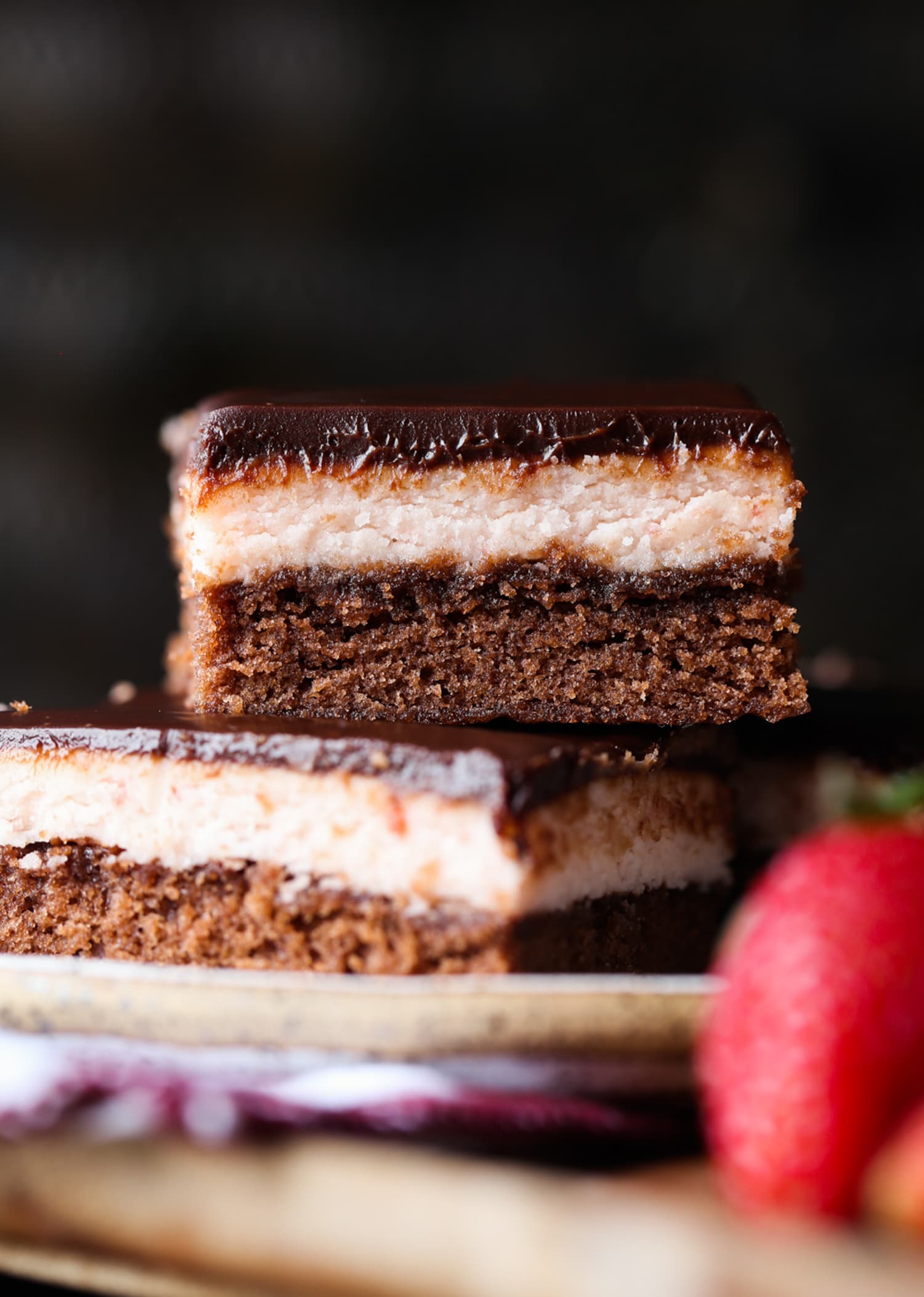 Three layer fudge brownies topped with strawberry frosting and chocolate ganache stacked