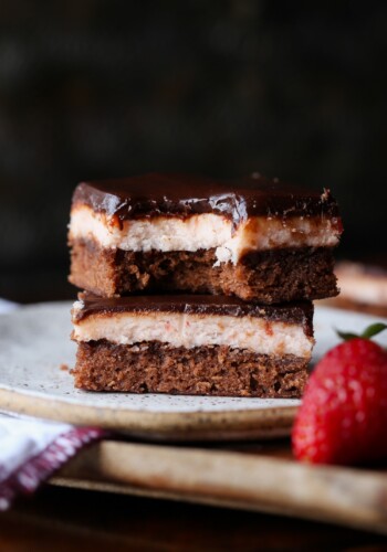 Layered Strawberry Brownies stacked on a plate with a bite taken out.