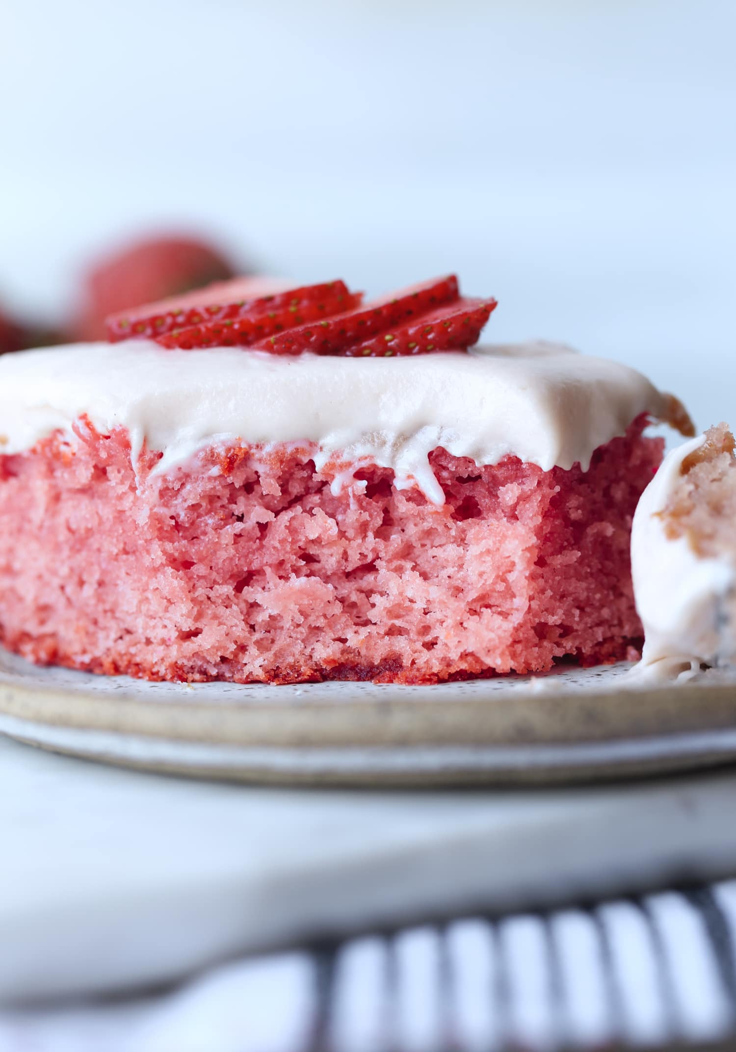 a slice of strawberry cake on a plate with a piece missing