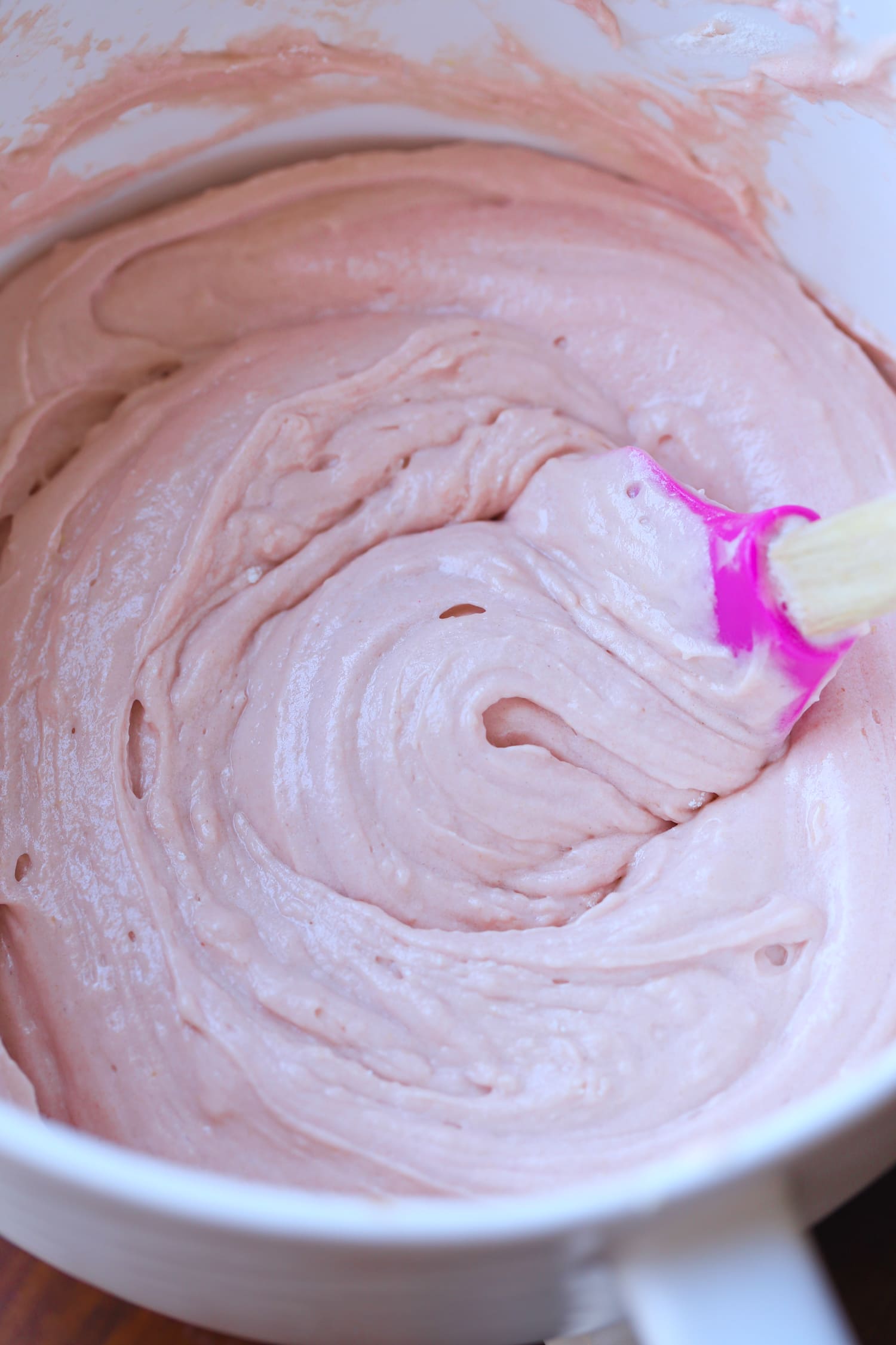 strawberry cream cheese frosting in a mixing bowl with a spatula